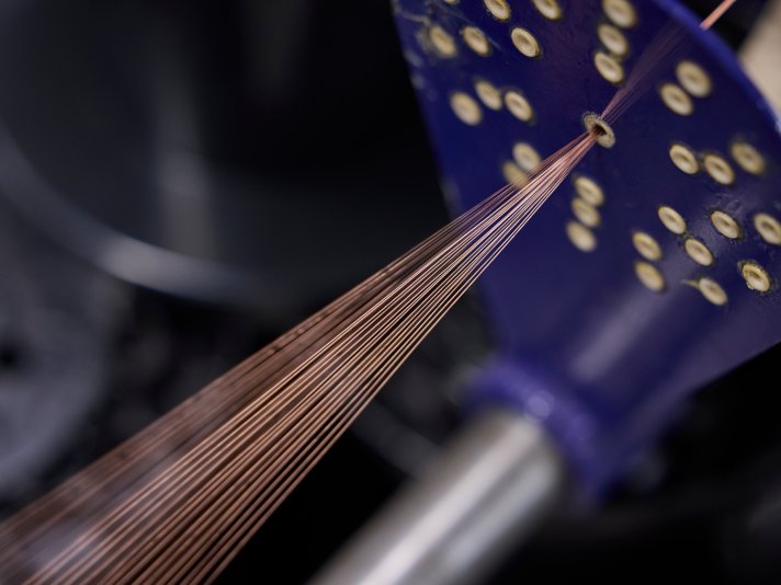 Kupferdrähte werden durch eine Öffnung einer Produktionsmaschine geführt