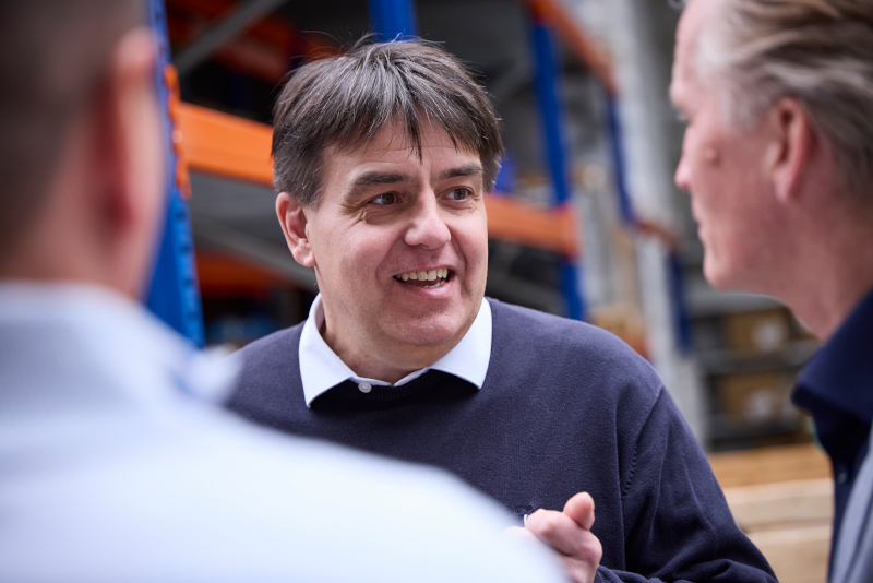 Drei Personen im Gespräch in einer Lager- oder Produktionshalle