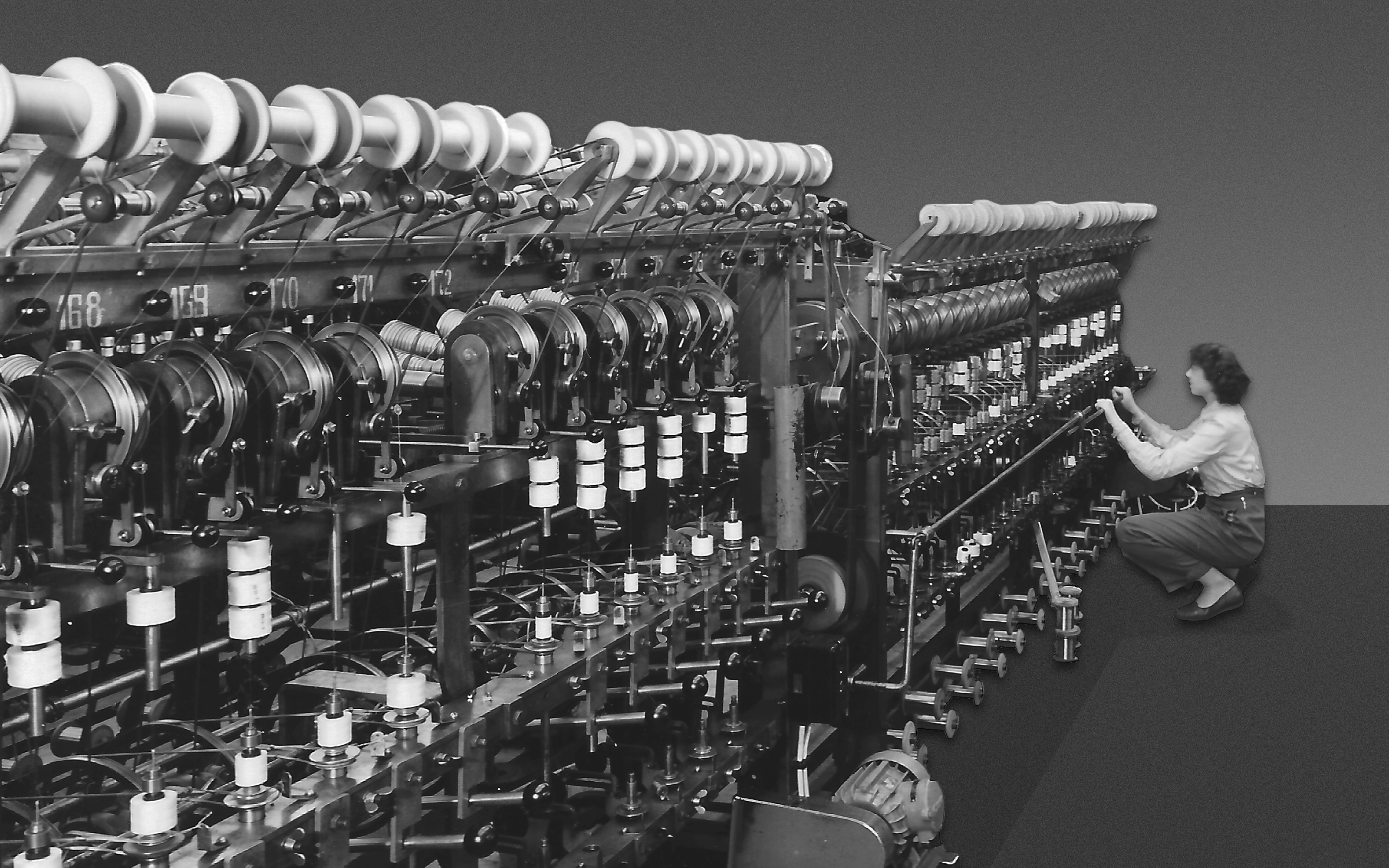 Historische Drahtumspinnmaschine mit Mitarbeitender in der Produktion